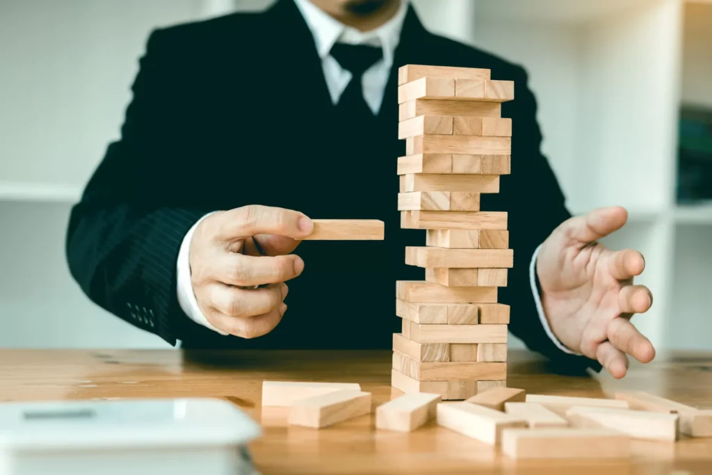 Person pulling a wooden block out of a fragile structure